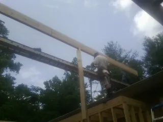 Carpenter setting a ridge beam over a new addition frame — Ice Dam Removal by Roofing Brothers in Upton