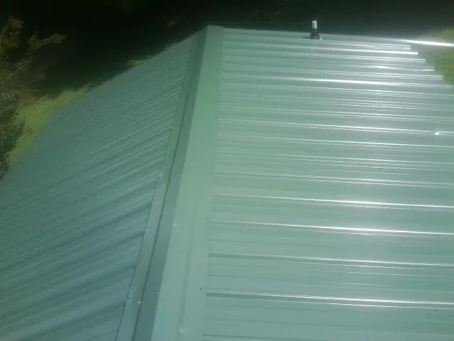 New green metal panels meeting at the ridge of a roof — Flat Roof Repair work by our crew in Upton
